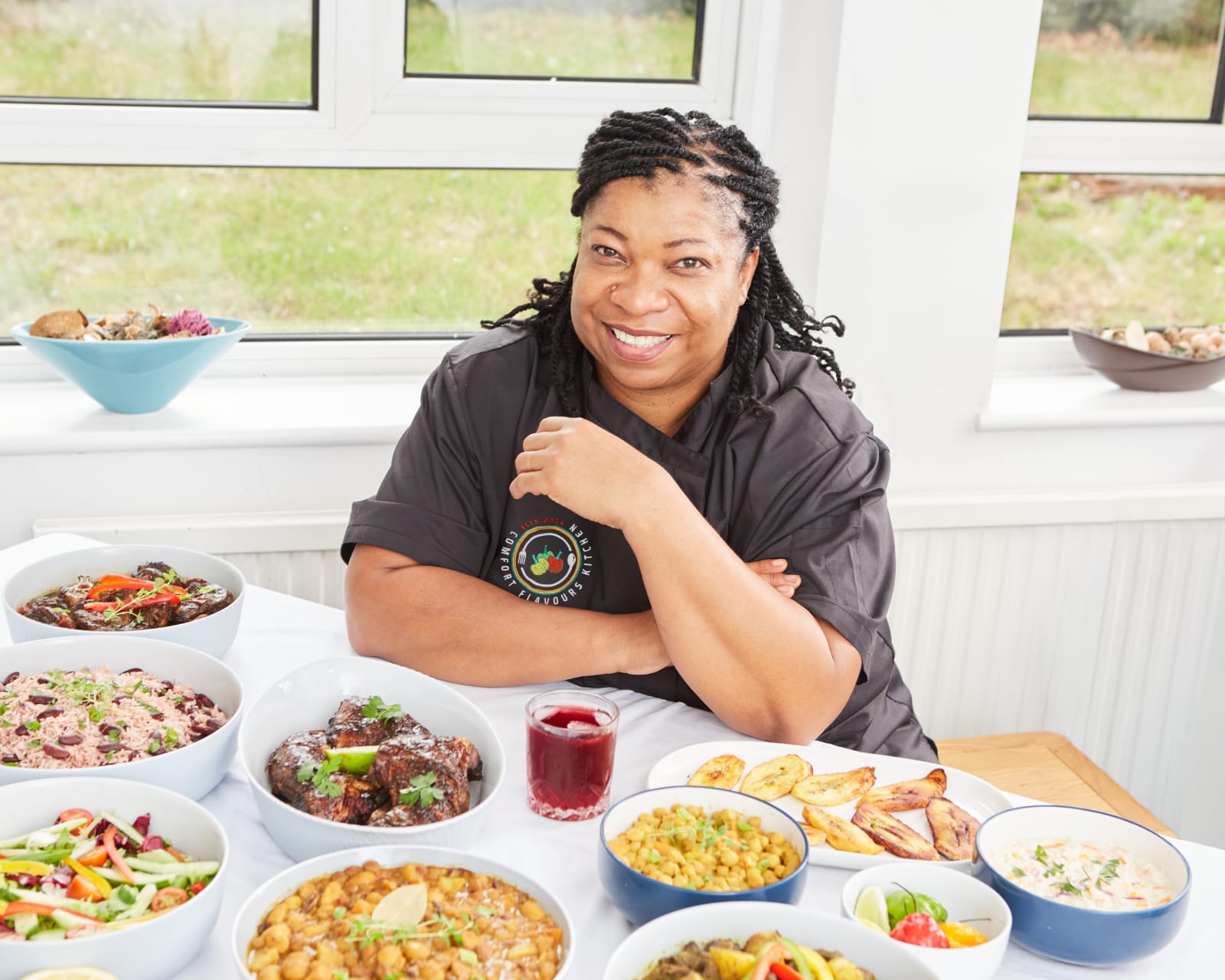 Claudette surrounded by freshly prepared Jamaican dishes